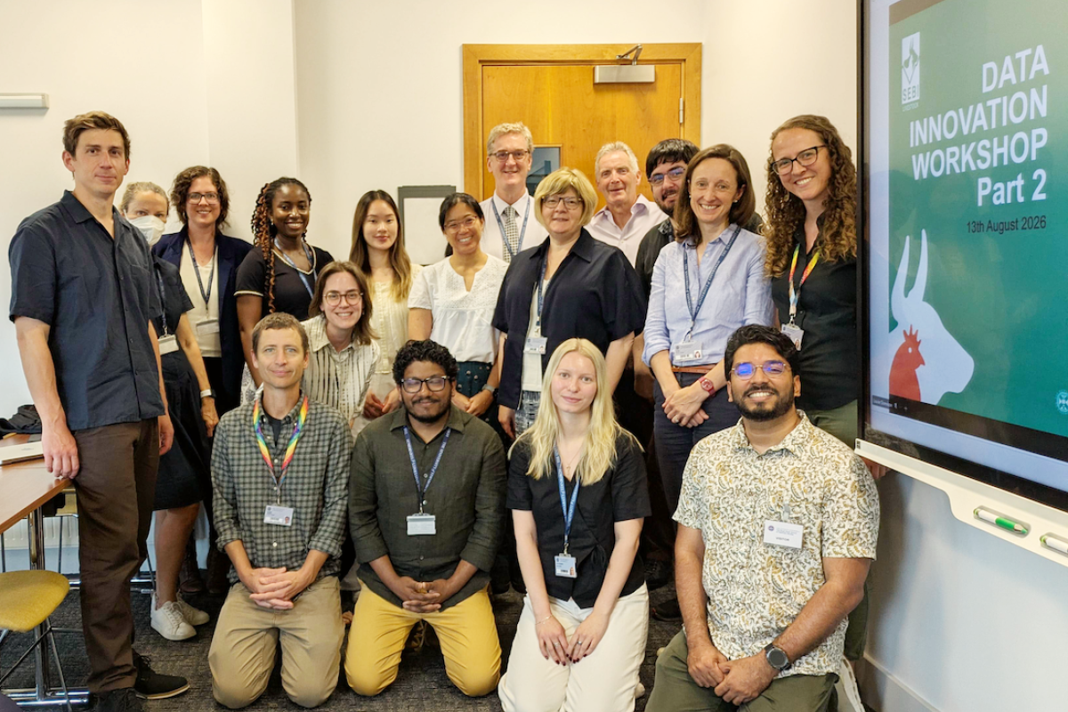 A group of people pose of mixed genders and ethnicities pose for a picture in a meeting room.